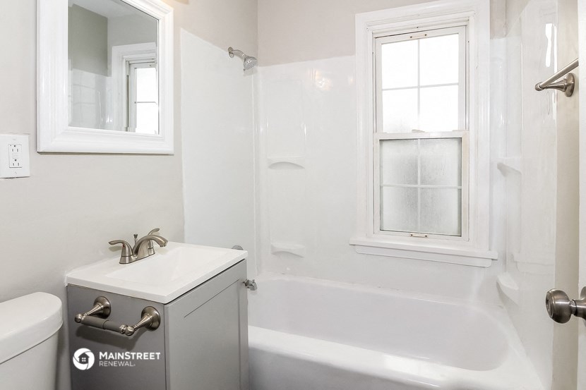 a white bathroom with a tub and a sink and a window