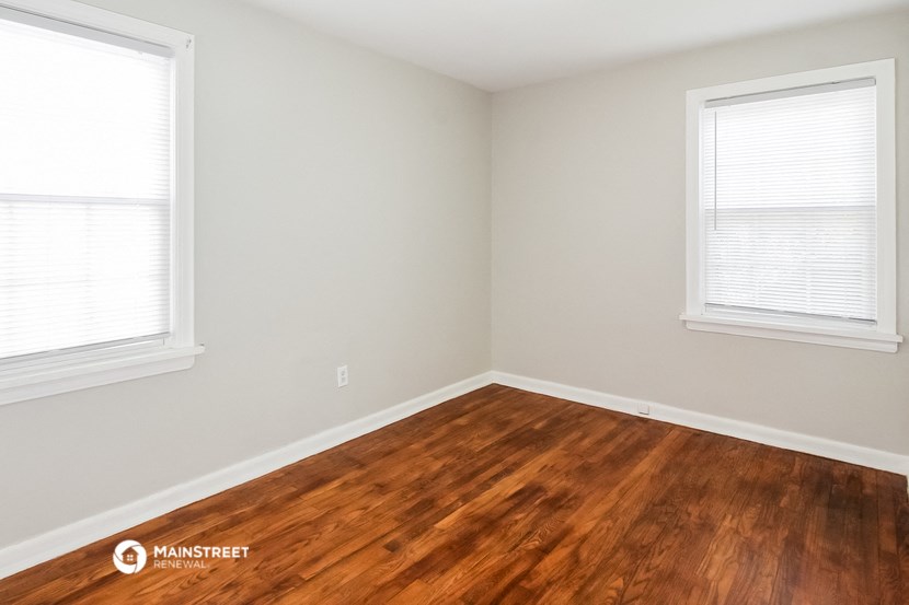 the upstairs bedroom with hardwood floors and two windows