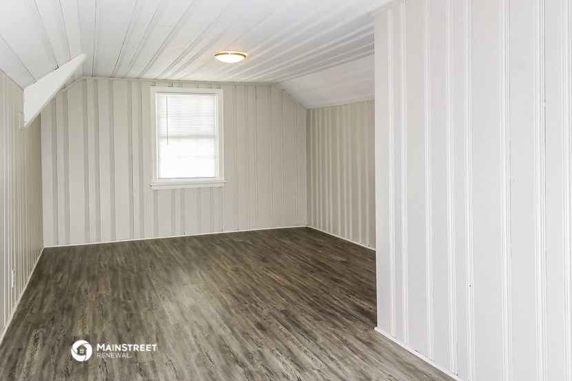 an empty room with white walls and wood floors and a window