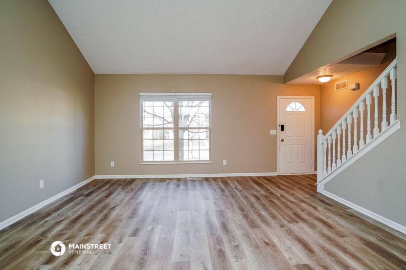 the spacious living room with hardwood floors and a staircase