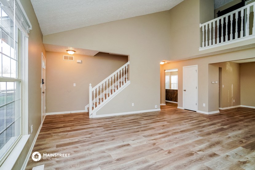a living room with a staircase and a hard wood floor