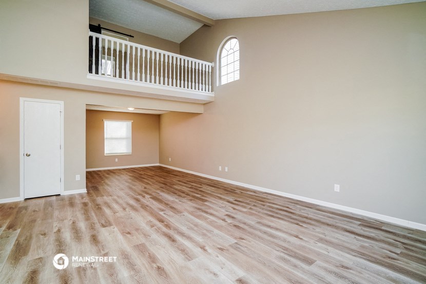the spacious living room with hardwood floors and a large window