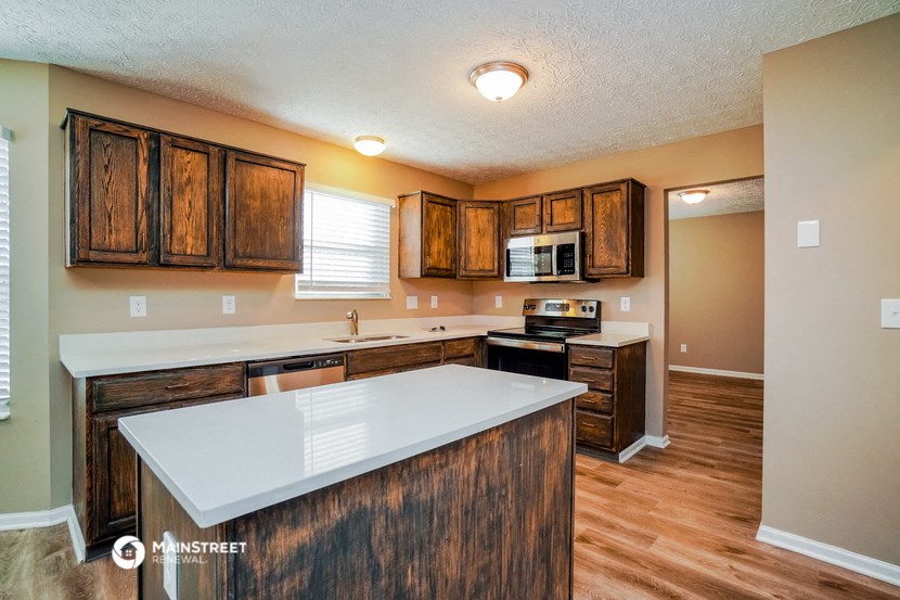 a kitchen with a white counter top and wooden cabinets