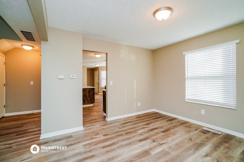 the living room and dining room with wood flooring and a large window