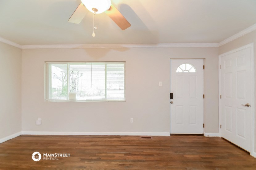 the living room with a white door and a ceiling fan