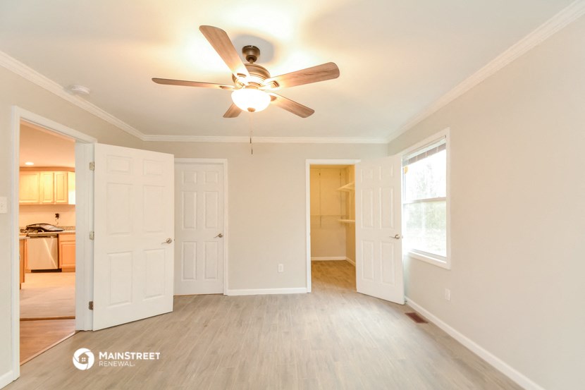 a living room with a ceiling fan and a door to a kitchen