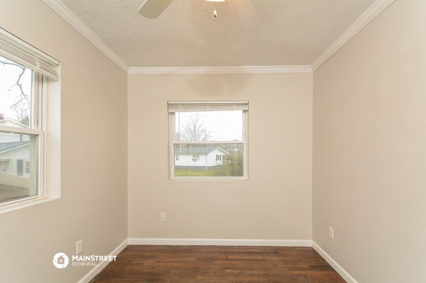 an empty room with a window and a wooden floor