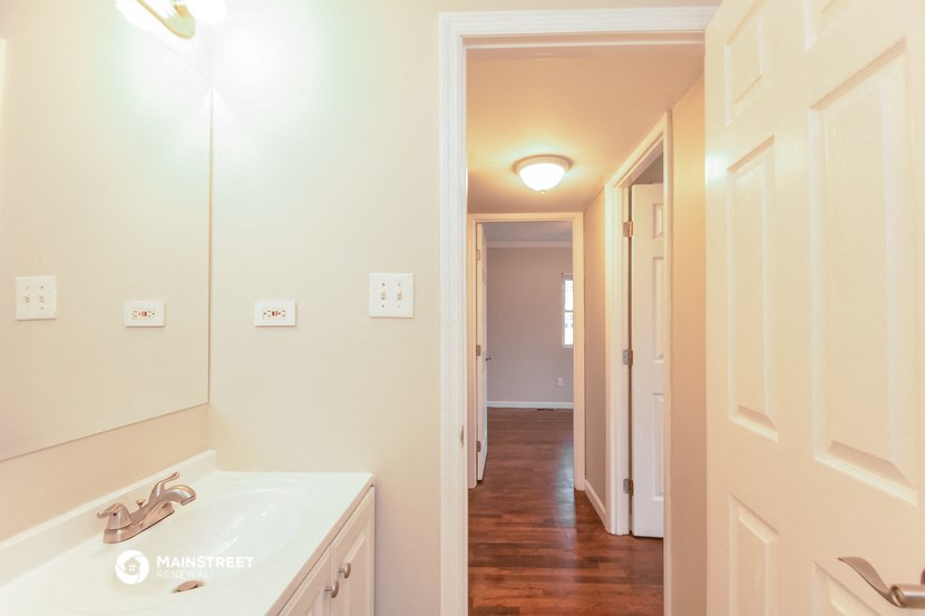 a bathroom with a white sink and a hallway in the background