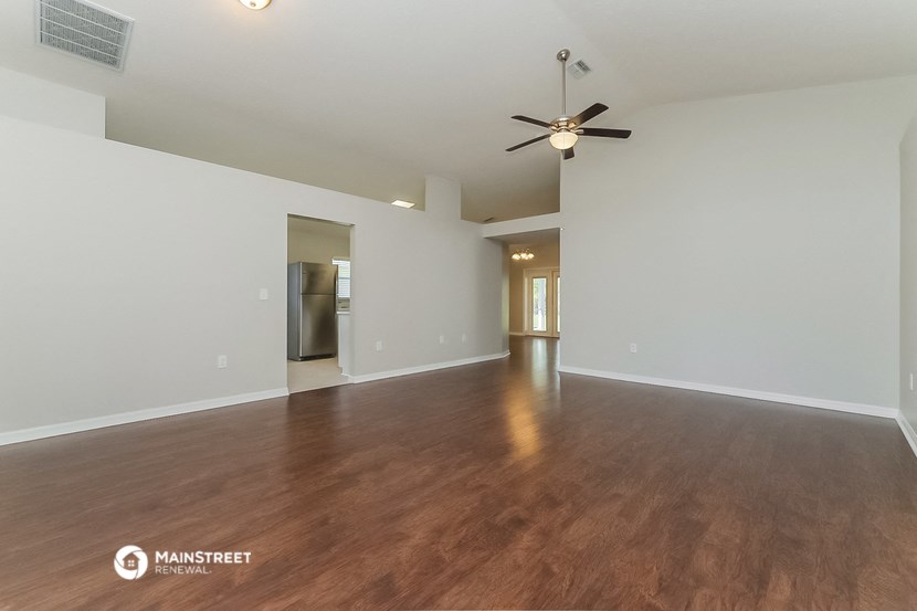 the living room and dining room of an empty house with a ceiling fan