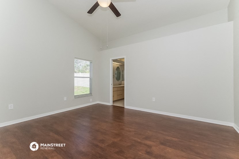 an empty living room with wood flooring and a ceiling fan