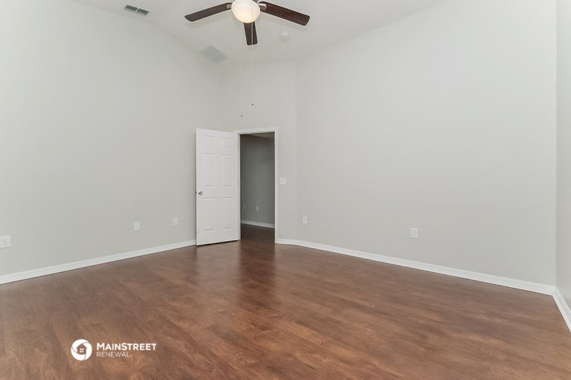 an empty living room with wood flooring and a ceiling fan