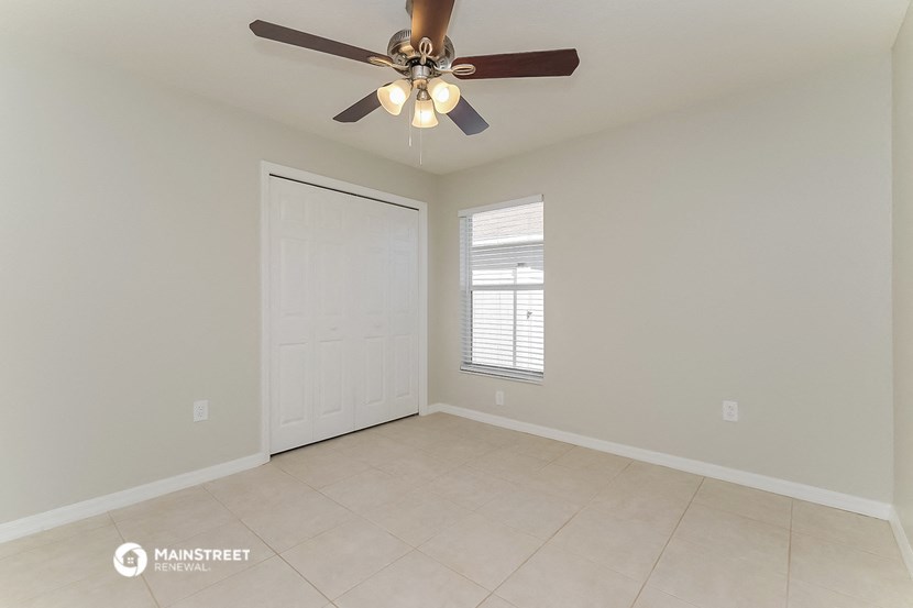 the spacious living room with ceiling fan and tiled floor