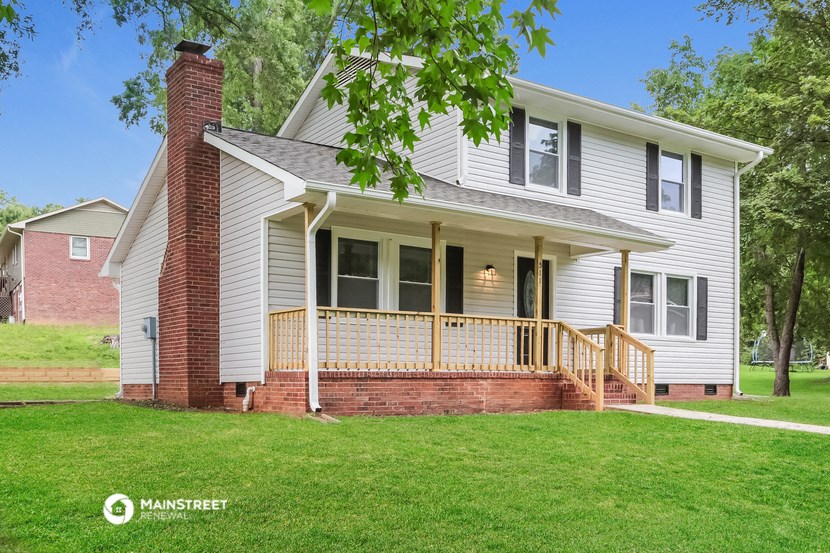 a white house with a porch on a green lawn