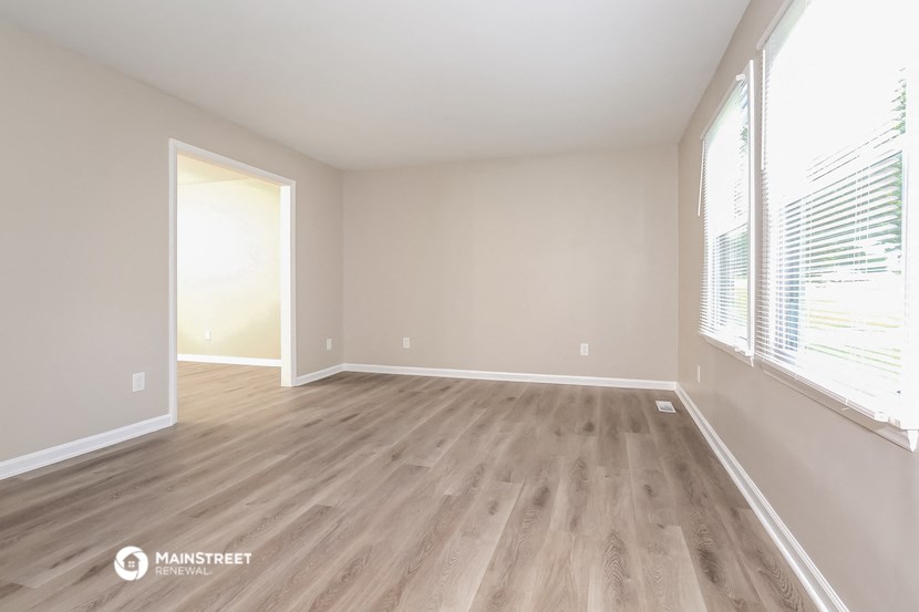 an empty living room with wood flooring and large windows