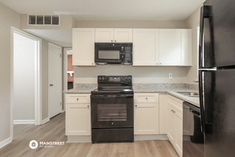 a renovated kitchen with black appliances and white cabinets