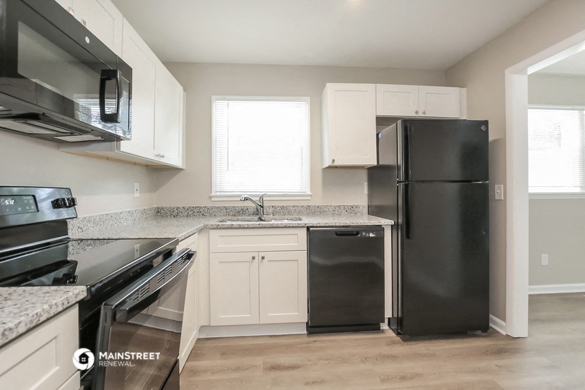 a kitchen with white cabinets and black appliances and a stainless steel refrigerator
