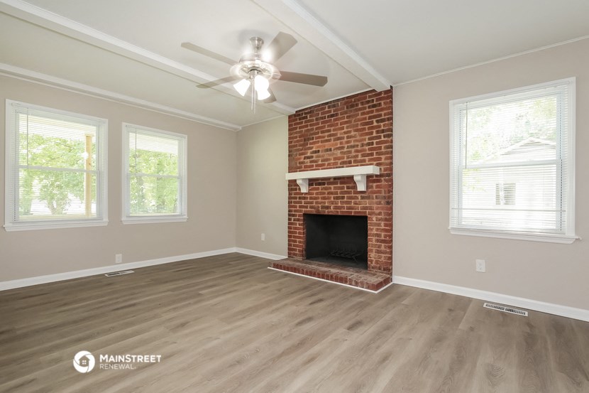 the living room with a brick fireplace and a ceiling fan