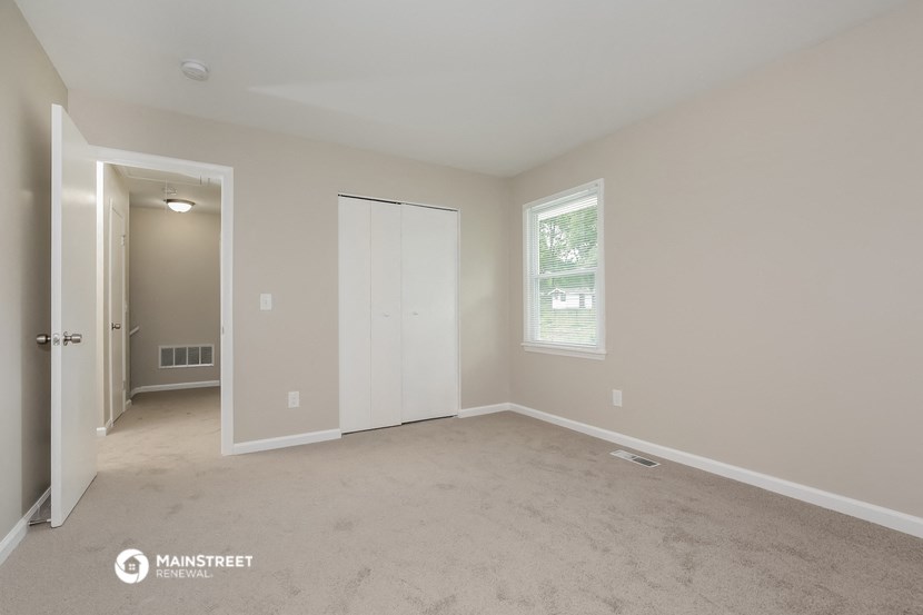 a bedroom with a carpeted floor and a door to a closet