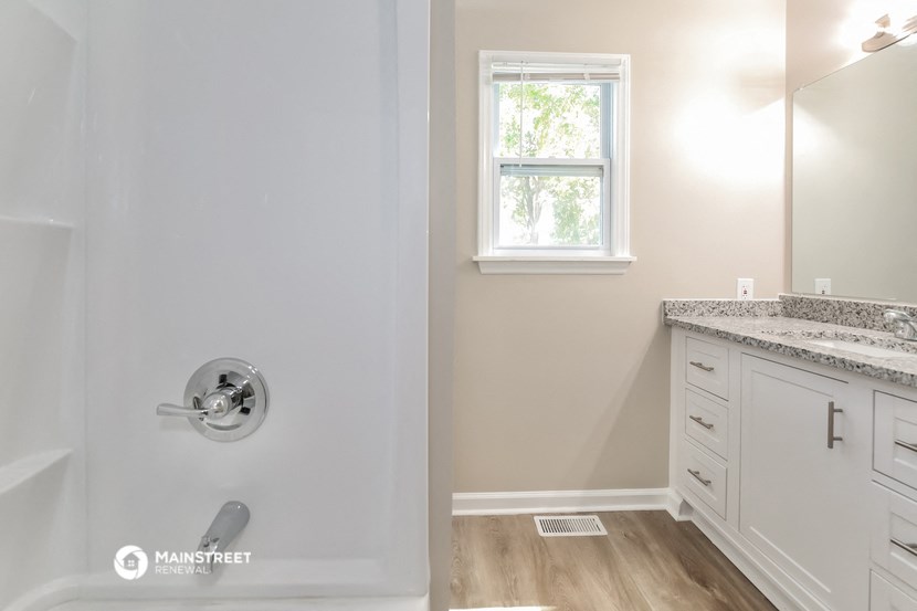 a bathroom with a shower and a sink and a window