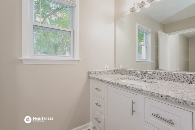 a bathroom with white cabinets and granite counter tops and a mirror