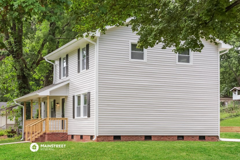 a white house with a front porch and a tree