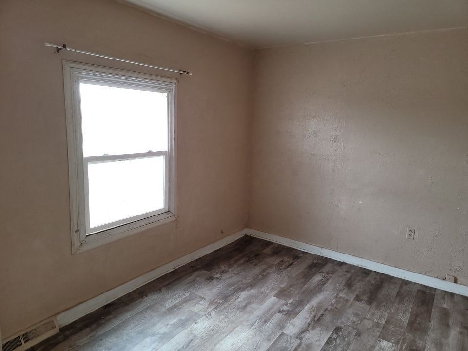 an empty room with a window and wooden floors