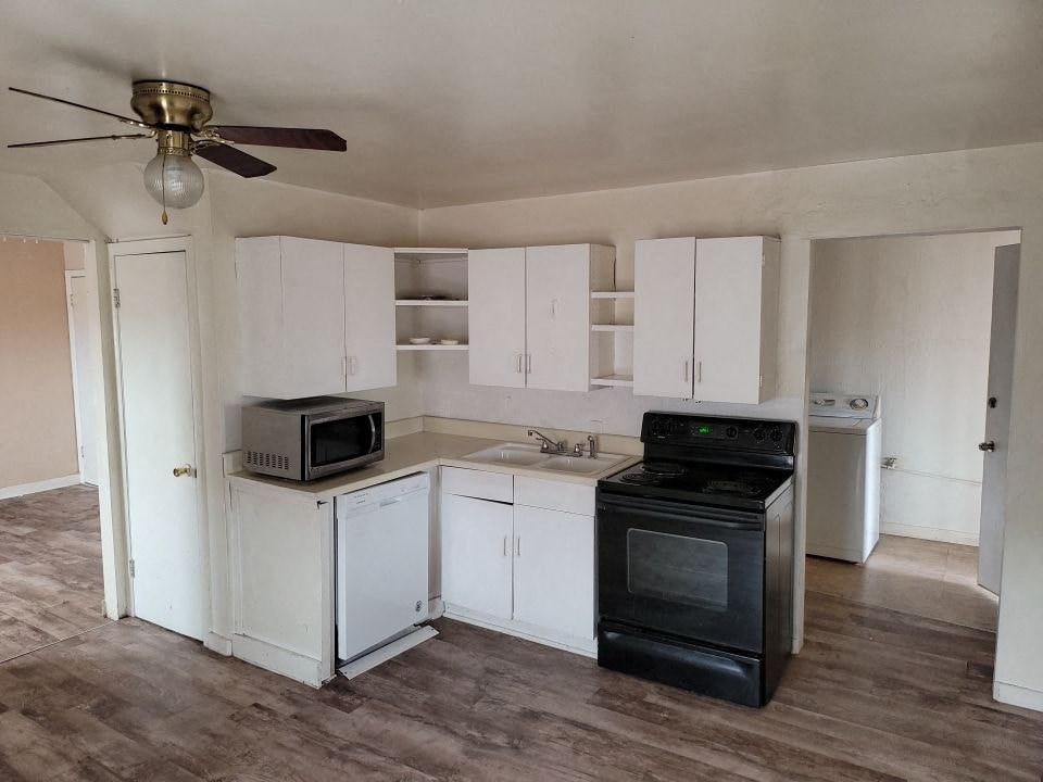 an empty kitchen with white cabinets and black appliances
