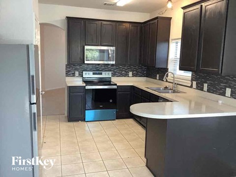 A kitchen with black cabinets and a white counter.