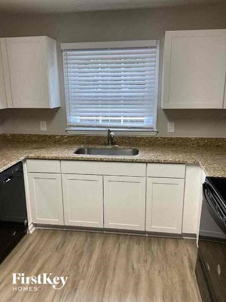 A kitchen with white cabinets and a granite countertop.