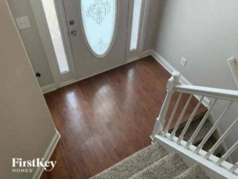 a hallway with stairs and a door with wood floors