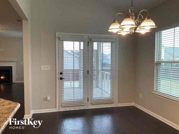 an empty living room with white doors and a chandelier