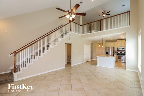 A spacious living room with a staircase and a kitchen in the background.