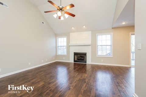 A spacious living room with a fireplace and a ceiling fan.