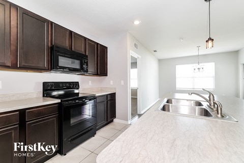 A kitchen with dark brown cabinets and a stove top oven.