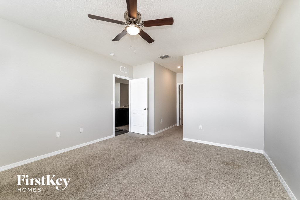 A spacious room with a ceiling fan and carpeted floor.