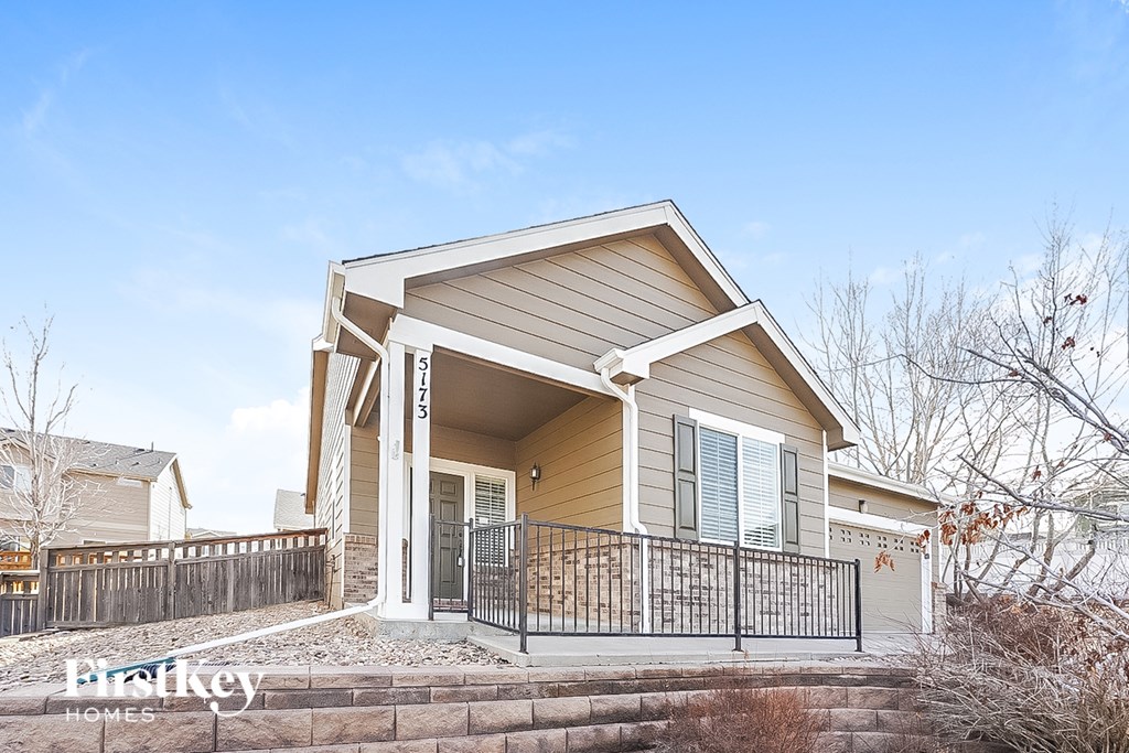 the front of a house with a porch and a fence