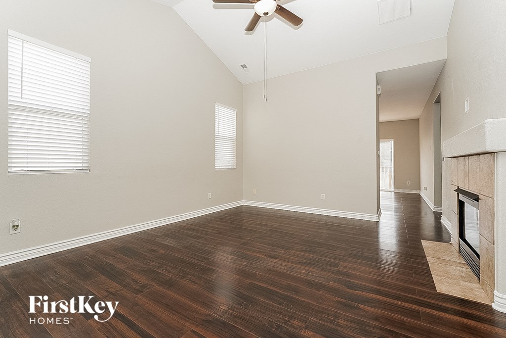 an empty living room with wood flooring and a ceiling fan