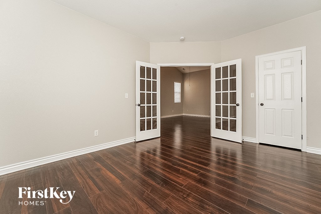 an empty living room with wood floors and white doors