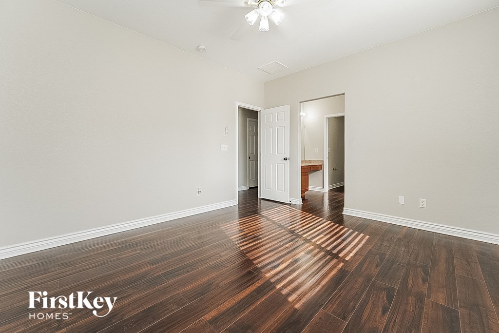 a spacious living room with hardwood flooring and a door to a bedroom
