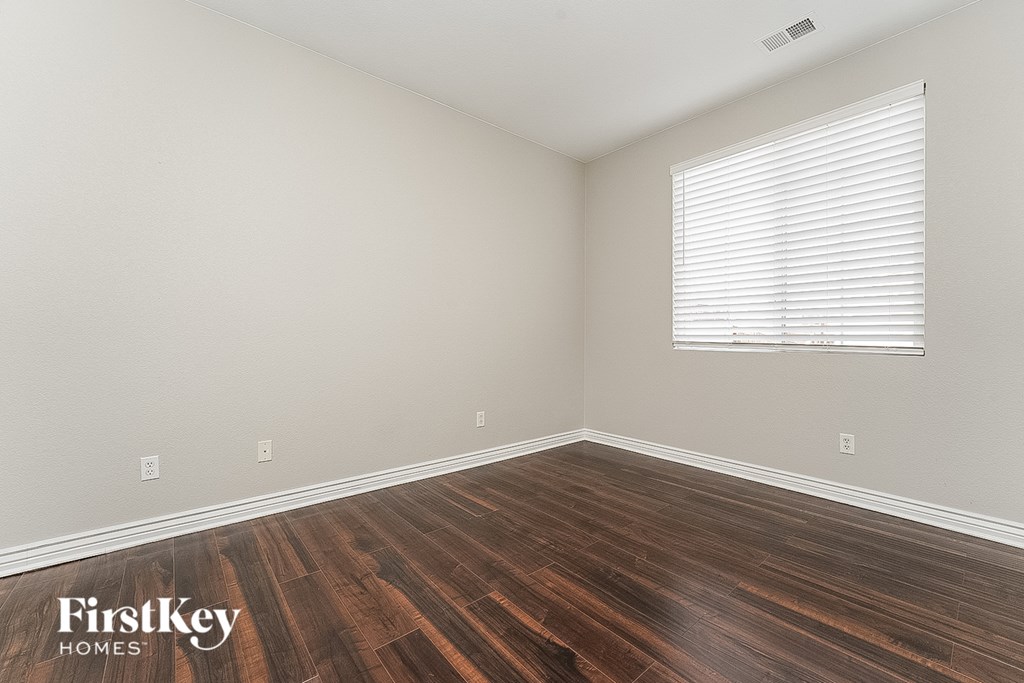 the spacious living room with wood flooring and a window