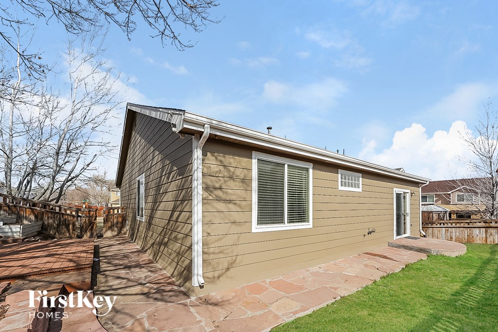 the exterior of a small house with a yard and a fence