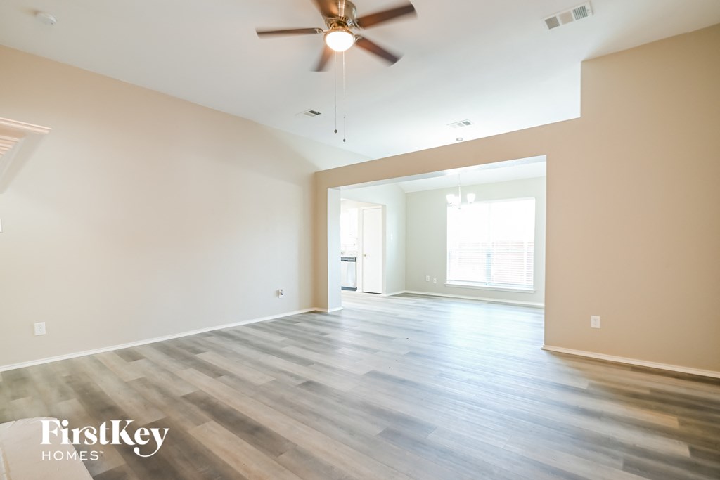 an empty living room with wood floors and a ceiling fan