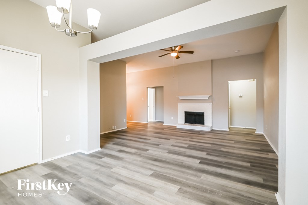 an empty living room with a fireplace and wood flooring
