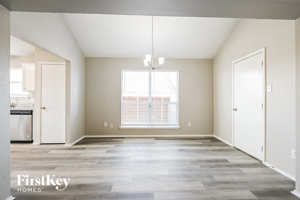 an empty living room with a large window and a kitchen