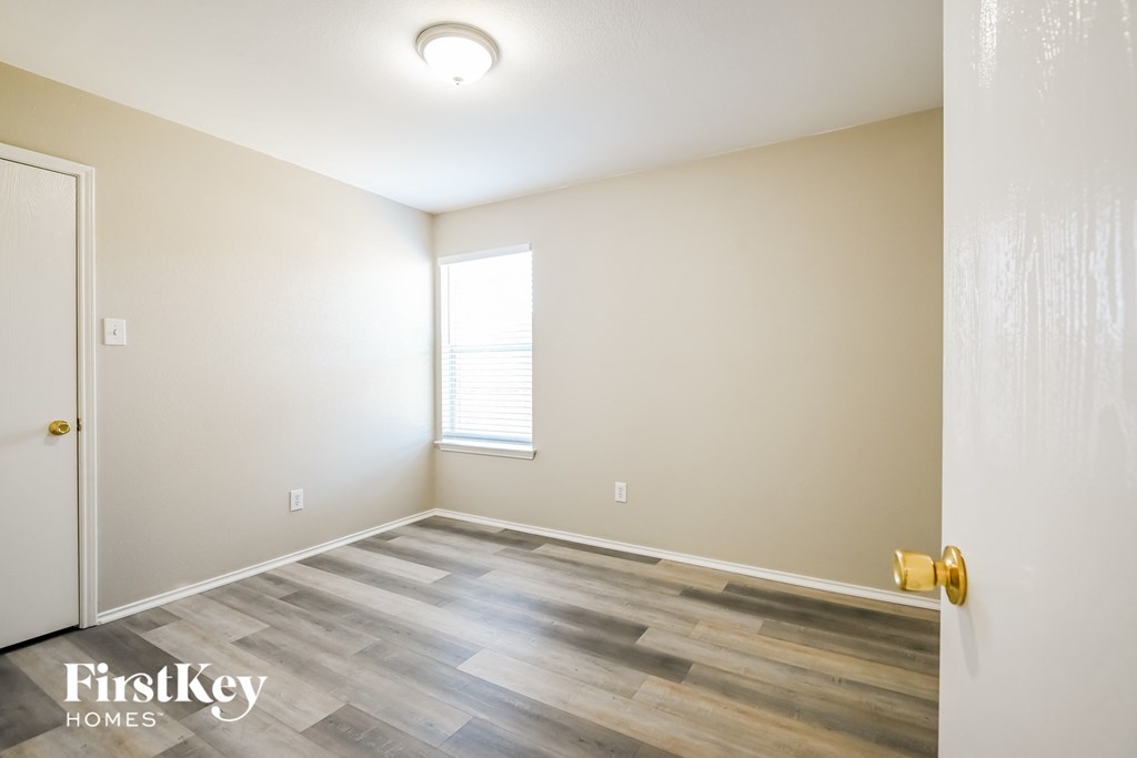 a room with wood floors and white walls and a window