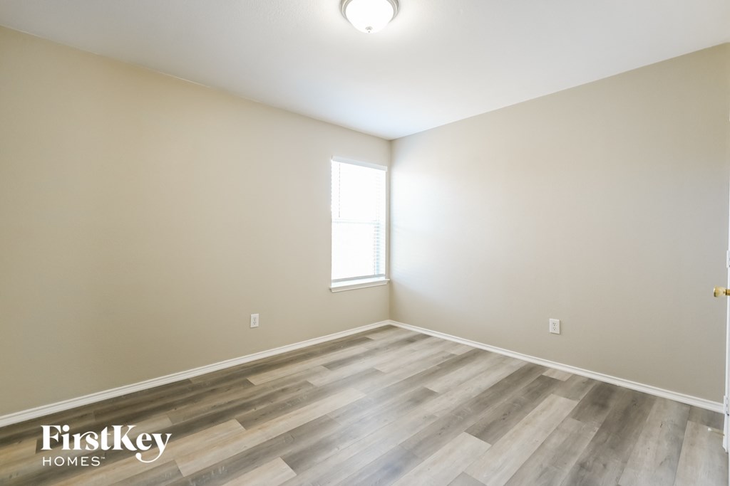 the spacious living room with hardwood flooring and a window
