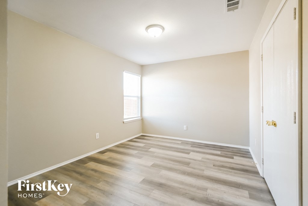 a room with wood flooring and white walls and a window