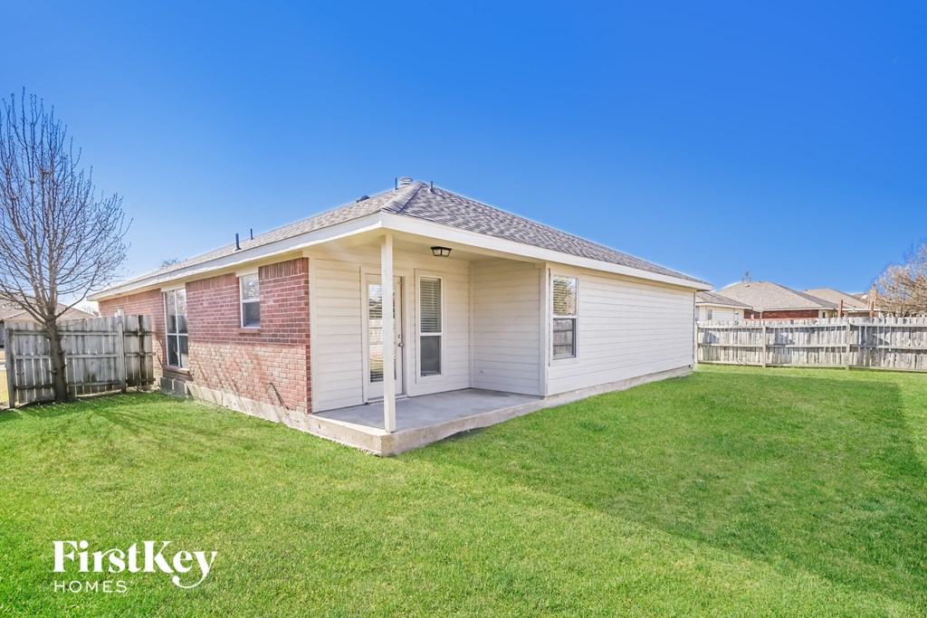 a small white house with a grass yard and a fence