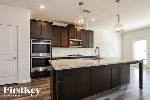 A kitchen with dark brown cabinets and granite countertops.