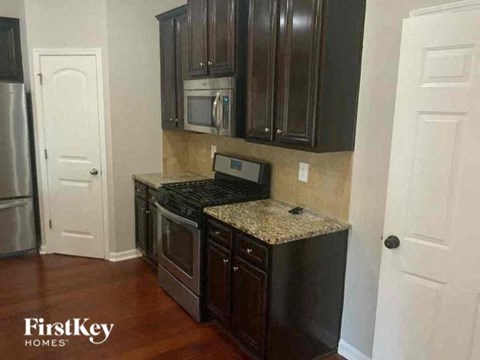 A kitchen with dark brown cabinets and a granite countertop.